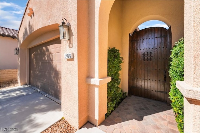 12276 Caminita Pl, Las Vegas, NV 89138 - view of exterior entry with a gate, stucco siding, and concrete driveway
