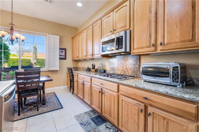 12276 Caminita Pl, Las Vegas, NV 89138 - kitchen featuring stainless steel appliances, a chandelier, light stone countertops, light tile patterned flooring, and decorative backsplash