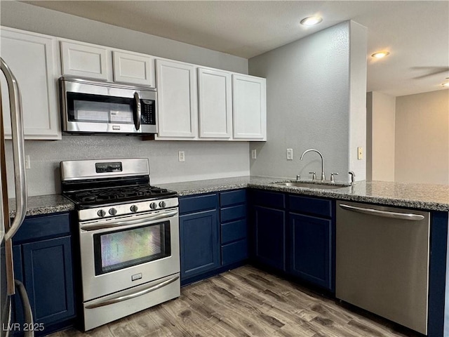 9165 Beauchamp Ave, Las Vegas, NV 89148 - kitchen featuring stainless steel appliances, blue cabinetry, white cabinetry, light wood-style flooring, and light stone countertops