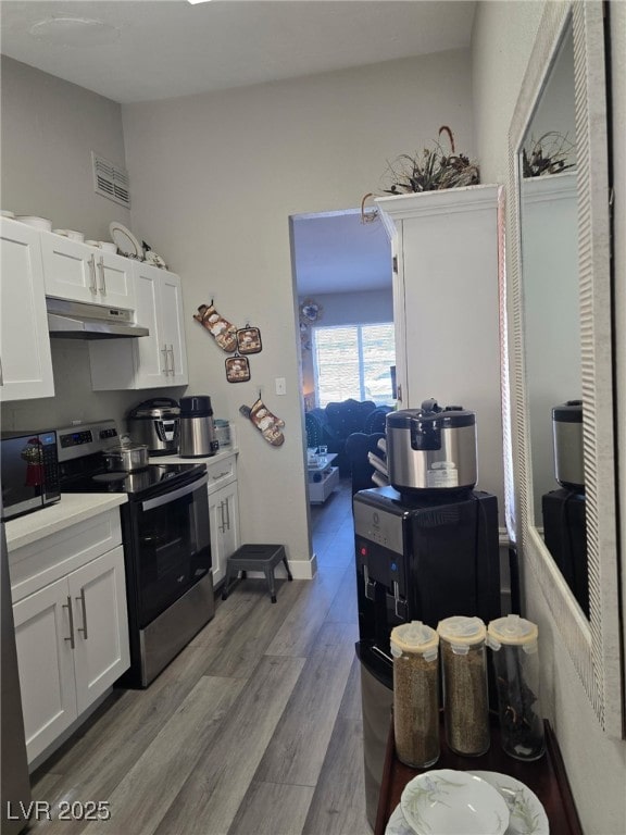 1713 Fairfield Ave, Las Vegas, NV 89102 - kitchen with stainless steel appliances, under cabinet range hood, white cabinetry, and wood finished floors