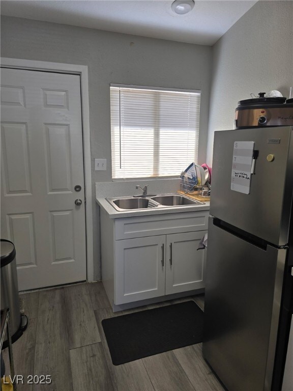 1713 Fairfield Ave, Las Vegas, NV 89102 - kitchen featuring freestanding refrigerator, light wood-style floors, white cabinets, and light countertops