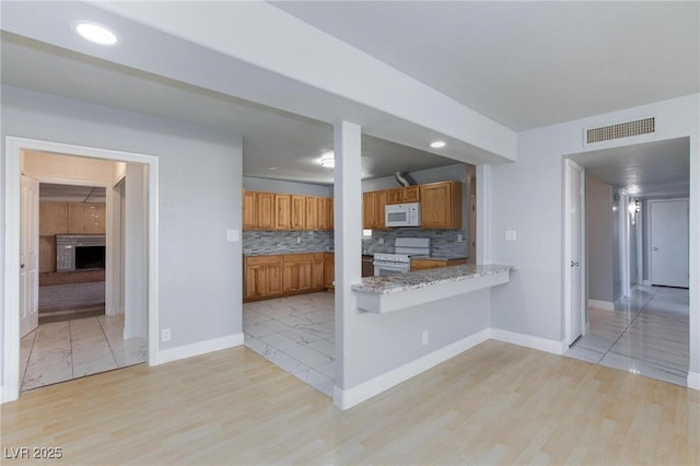 6317 Alta Dr, Las Vegas, NV 89107 - kitchen with white appliances, brown cabinetry, light wood-style flooring, decorative backsplash, and recessed lighting