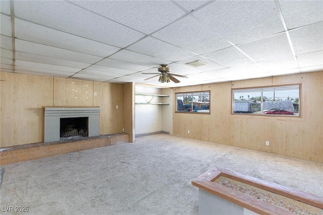 6317 Alta Dr, Las Vegas, NV 89107 - unfurnished living room with carpet, a fireplace, wooden walls, ceiling fan, and a paneled ceiling
