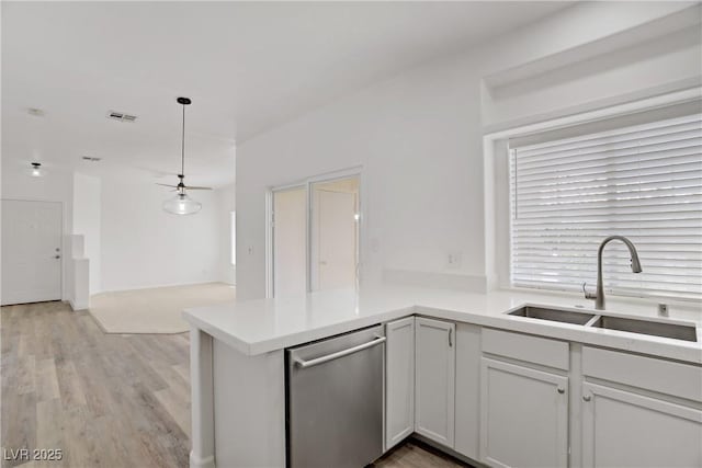 5112 Harvest Time St Unit 201, Las Vegas, NV 89130 - kitchen with stainless steel dishwasher, a peninsula, ceiling fan, light wood-style flooring, and hanging light fixtures