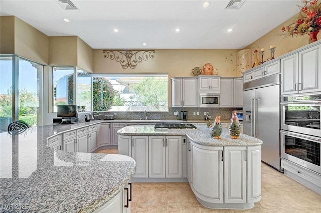 4936 Mountain Foliage Dr, Las Vegas, NV 89148 - kitchen with built in appliances, a kitchen island, recessed lighting, backsplash, and light stone countertops