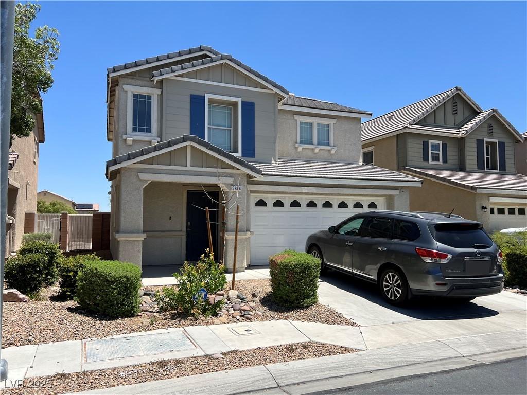 5824 Gemstone Peak St, North Las Vegas, NV 89031 - view of front of house with a garage, a tile roof, concrete driveway, stucco siding, and board and batten siding