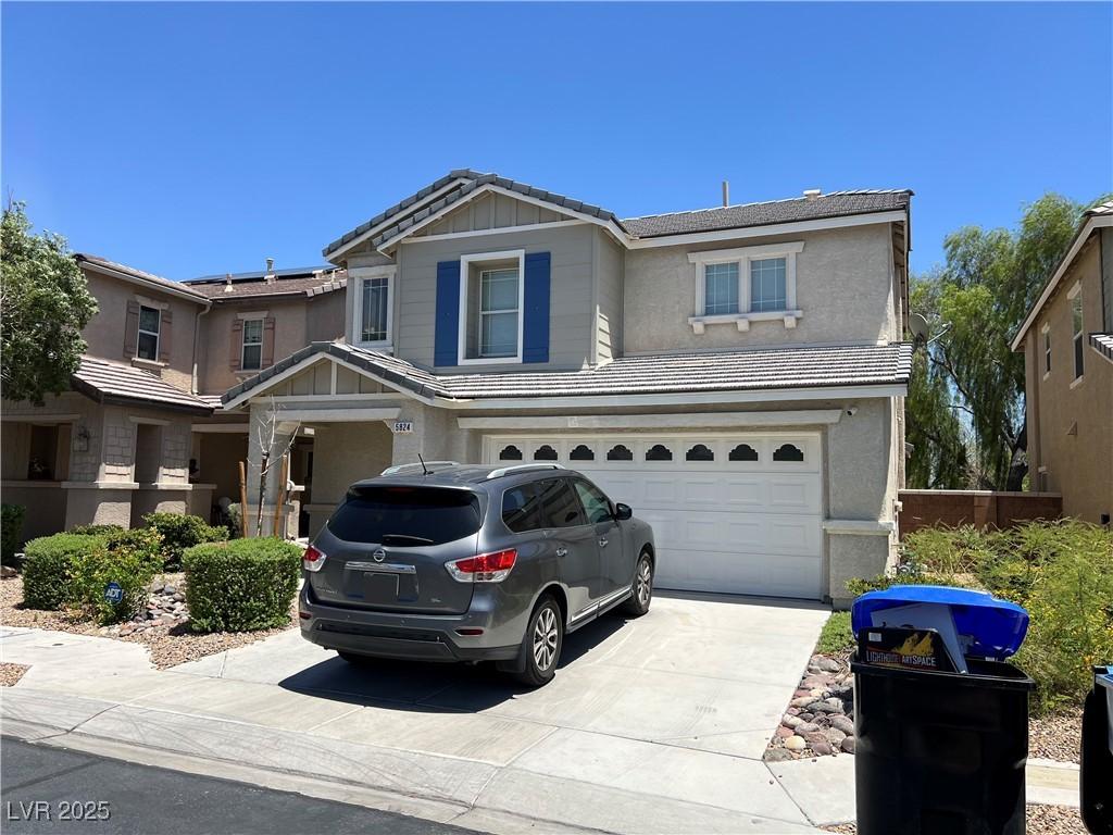 5824 Gemstone Peak St, North Las Vegas, NV 89031 - view of front of home with a garage, driveway, stucco siding, and a tiled roof