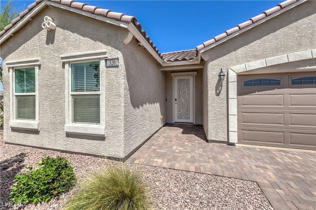 326 Zenith Crest St, Henderson, NV 89015 - view of exterior entry with stucco siding, a tile roof, and an attached garage