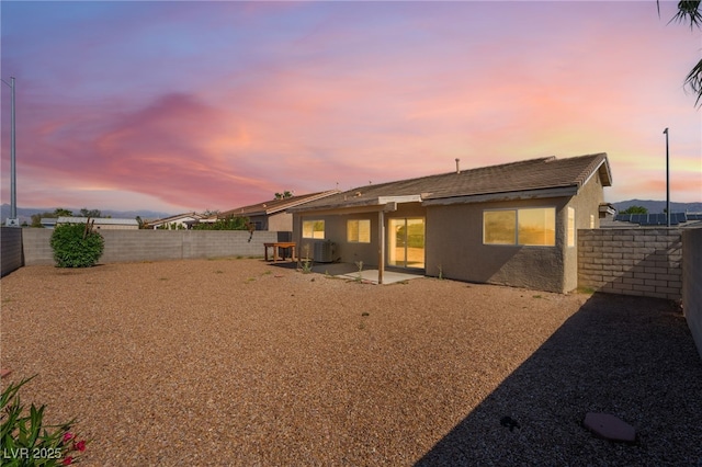 2111 Hollow Oak Ave, North Las Vegas, NV 89031 - back of property at dusk with stucco siding, a fenced backyard, and a patio