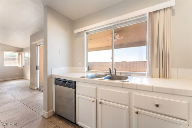 2111 Hollow Oak Ave, North Las Vegas, NV 89031 - kitchen featuring dishwasher, tile counters, white cabinets, light tile patterned floors, and vaulted ceiling