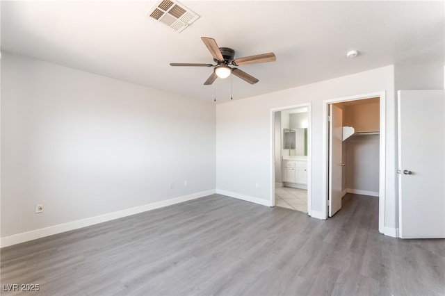2111 Hollow Oak Ave, North Las Vegas, NV 89031 - unfurnished bedroom featuring a spacious closet, wood finished floors, a closet, connected bathroom, and a ceiling fan