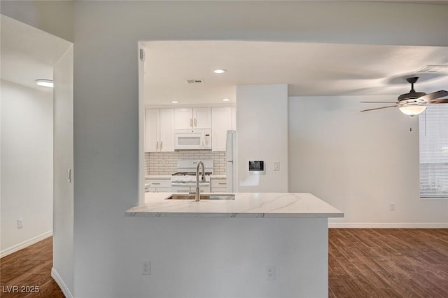2050 W Warm Springs Rd Unit 4512, Henderson, NV 89014 - kitchen featuring white appliances, tasteful backsplash, dark wood finished floors, ceiling fan, and white cabinets