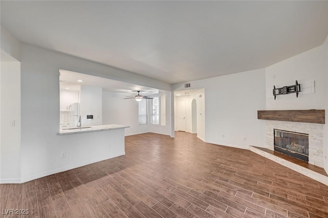 2050 W Warm Springs Rd Unit 4512, Henderson, NV 89014 - unfurnished living room featuring a fireplace, dark wood-style flooring, a ceiling fan, recessed lighting, and arched walkways