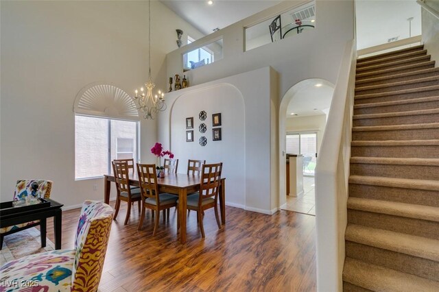 10952 Porto Foxi St, Las Vegas, NV 89141 - dining space featuring stairs, a high ceiling, wood finished floors, a chandelier, and arched walkways