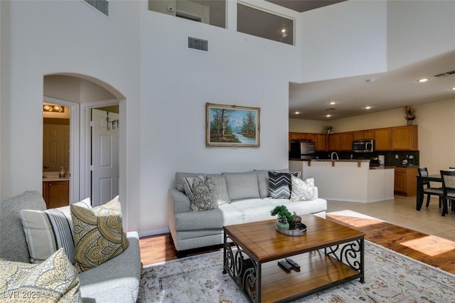 10952 Porto Foxi St, Las Vegas, NV 89141 - living room featuring arched walkways, a high ceiling, light wood-style floors, and recessed lighting