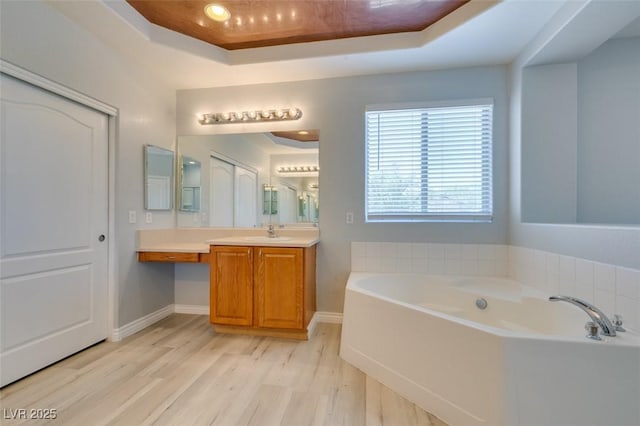 3941 Copper Stone Ct, North Las Vegas, NV 89032 - bathroom with a raised ceiling, a garden tub, wood finished floors, and vanity