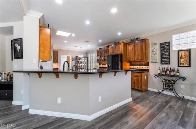 10331 Rio De Thule Ln, Las Vegas, NV 89135 - kitchen featuring black refrigerator with ice dispenser, brown cabinetry, a breakfast bar area, dark countertops, and ornamental molding