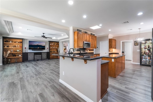 10331 Rio De Thule Ln, Las Vegas, NV 89135 - kitchen with appliances with stainless steel finishes, ornamental molding, dark countertops, brown cabinets, and a breakfast bar