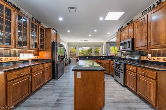10331 Rio De Thule Ln, Las Vegas, NV 89135 - kitchen with stainless steel appliances, dark countertops, a peninsula, decorative backsplash, and light wood finished floors