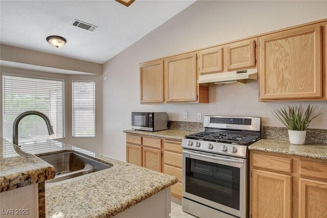 1981 Spring Lake Dr, Henderson, NV 89002 - kitchen featuring stainless steel range with gas stovetop, light brown cabinets, under cabinet range hood, lofted ceiling, and light stone countertops