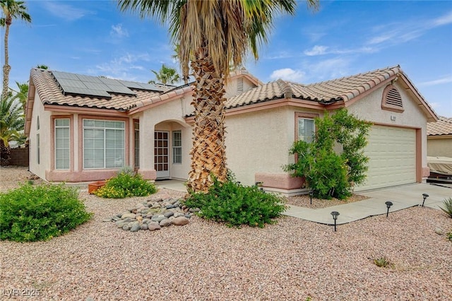 1981 Spring Lake Dr, Henderson, NV 89002 - view of front of house with stucco siding, an attached garage, roof mounted solar panels, a tiled roof, and driveway
