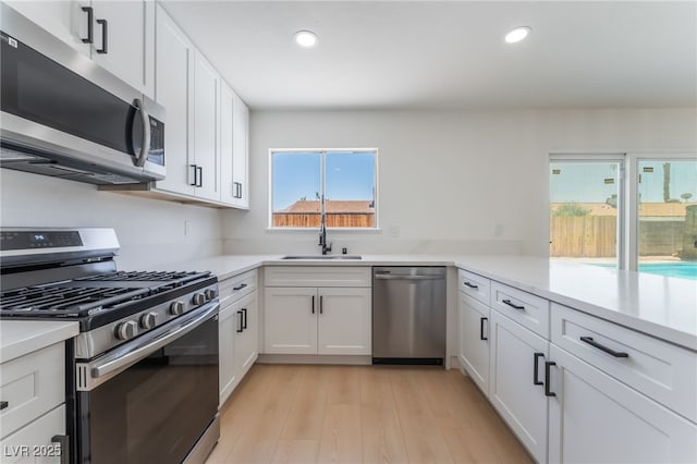 313 Agora Way, Las Vegas, NV 89110 - kitchen with stainless steel appliances, light countertops, white cabinetry, recessed lighting, and light wood finished floors