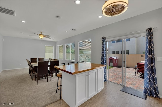 9131 Grand Sunburst Ct, Las Vegas, NV 89149 - kitchen with butcher block counters, white cabinets, recessed lighting, a ceiling fan, and a kitchen island