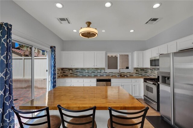 9131 Grand Sunburst Ct, Las Vegas, NV 89149 - kitchen with stainless steel appliances, backsplash, white cabinets, recessed lighting, and wooden counters