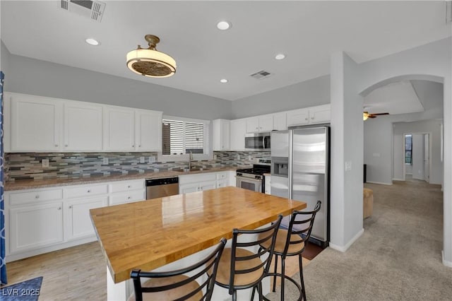 9131 Grand Sunburst Ct, Las Vegas, NV 89149 - kitchen featuring appliances with stainless steel finishes, a ceiling fan, backsplash, white cabinets, and arched walkways
