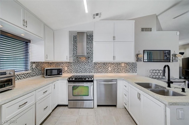 1708 Anzio St, Las Vegas, NV 89108 - kitchen featuring stainless steel appliances, wall chimney exhaust hood, a peninsula, vaulted ceiling, and white cabinetry