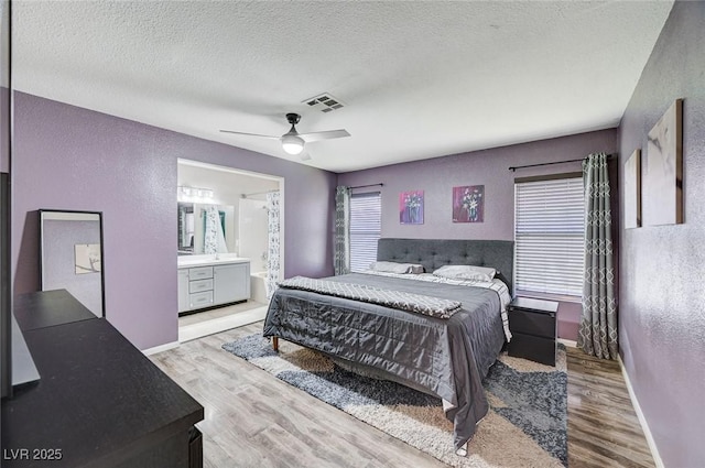 1708 Anzio St, Las Vegas, NV 89108 - bedroom featuring a textured wall, wood finished floors, multiple windows, a textured ceiling, and connected bathroom