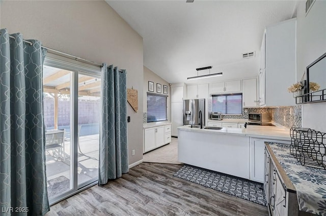 1708 Anzio St, Las Vegas, NV 89108 - kitchen with stainless steel fridge, light wood-style flooring, lofted ceiling, tasteful backsplash, and white cabinetry