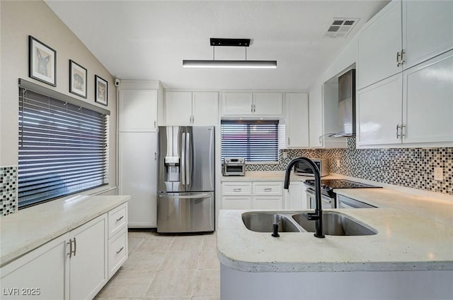 1708 Anzio St, Las Vegas, NV 89108 - kitchen featuring stainless steel fridge with ice dispenser, wall chimney range hood, tasteful backsplash, and white cabinets