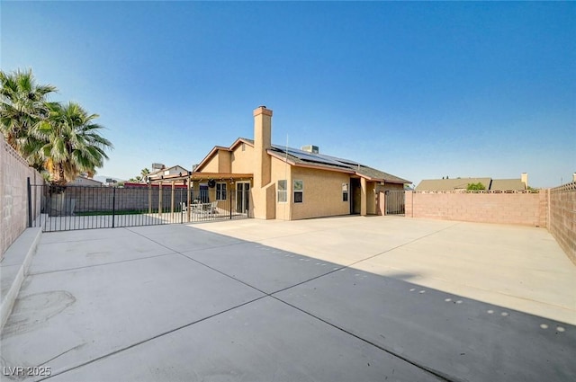 1708 Anzio St, Las Vegas, NV 89108 - back of property with solar panels, a fenced backyard, a patio area, stucco siding, and a chimney