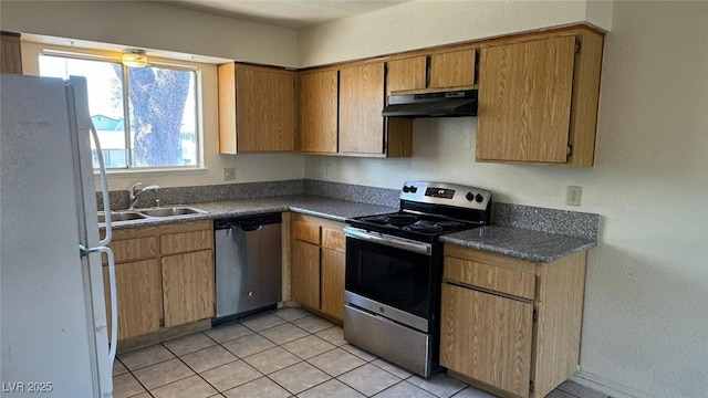 3412 Mercury St Unit I, North Las Vegas, NV 89030 - kitchen with appliances with stainless steel finishes, under cabinet range hood, dark countertops, light tile patterned floors, and brown cabinetry