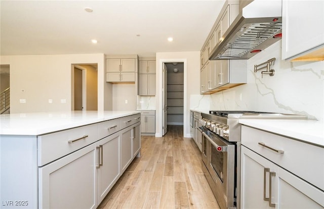 7199 Twilight Rider Ct, Las Vegas, NV 89118 - kitchen with ventilation hood, stainless steel stove, light wood finished floors, decorative backsplash, and recessed lighting