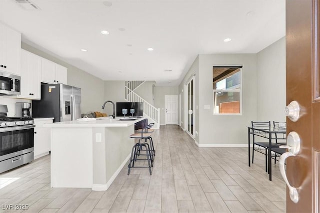 4533 Queens Hill St, North Las Vegas, NV 89031 - kitchen featuring appliances with stainless steel finishes, a kitchen island with sink, a breakfast bar, light wood-style floors, and recessed lighting