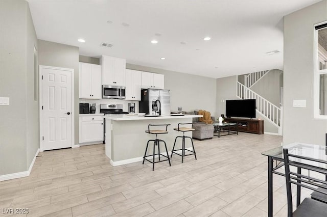 4533 Queens Hill St, North Las Vegas, NV 89031 - kitchen featuring stainless steel appliances, a breakfast bar, a center island with sink, white cabinets, and open floor plan