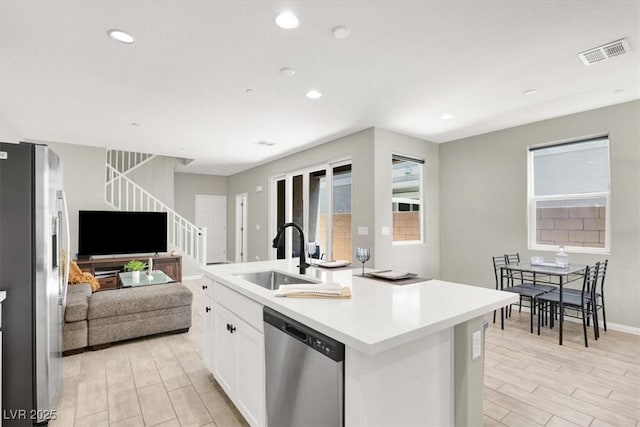 4533 Queens Hill St, North Las Vegas, NV 89031 - kitchen with stainless steel appliances, open floor plan, white cabinetry, wood tiled floors, and an island with sink