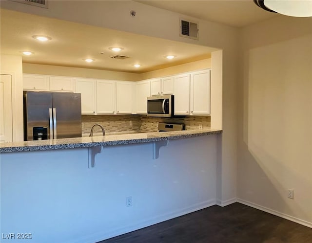 908 Duckhorn Ct Unit 102, Las Vegas, NV 89144 - kitchen with appliances with stainless steel finishes, a kitchen bar, white cabinets, decorative backsplash, and dark wood-type flooring