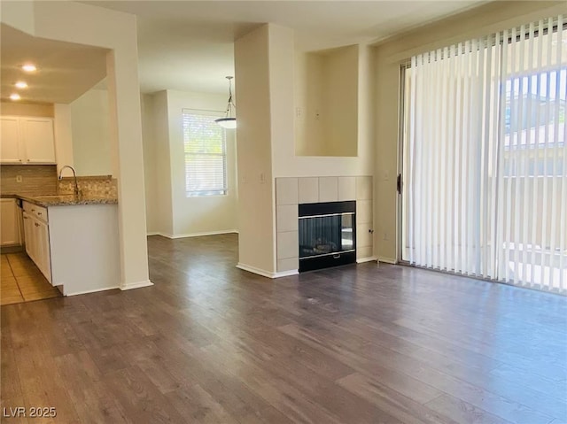 908 Duckhorn Ct Unit 102, Las Vegas, NV 89144 - unfurnished living room with dark wood-type flooring and a tiled fireplace