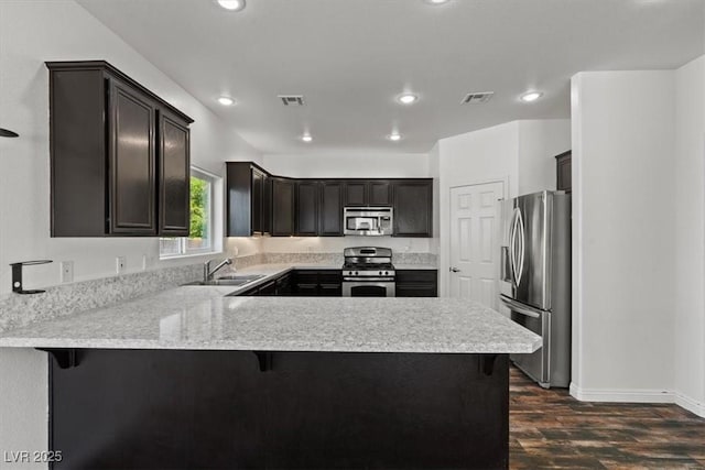 3632 Julia Waldene Ct, Las Vegas, NV 89129 - kitchen with appliances with stainless steel finishes, a peninsula, dark wood finished floors, light countertops, and recessed lighting