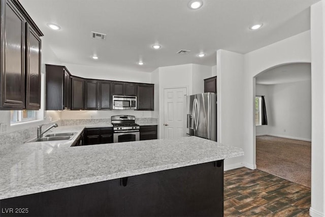 3632 Julia Waldene Ct, Las Vegas, NV 89129 - kitchen featuring stainless steel appliances, arched walkways, light countertops, a peninsula, and dark brown cabinetry