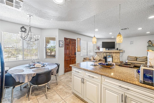 1001 Sulphur Springs Ln Unit 202, Las Vegas, NV 89128 - kitchen featuring a chandelier, light tile patterned floors, pendant lighting, light stone counters, and a textured ceiling