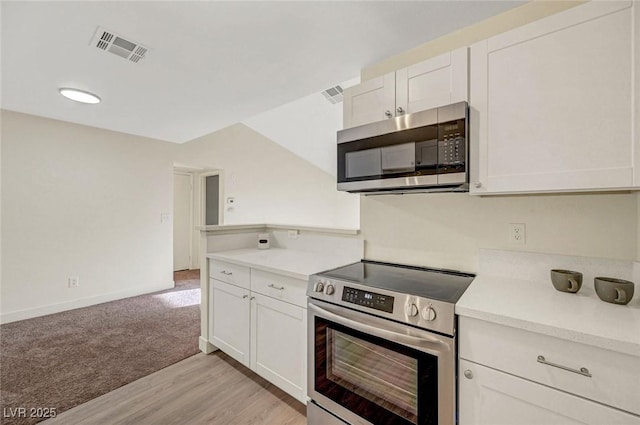 5161 Lindell Rd Unit 206, Las Vegas, NV 89118 - kitchen featuring appliances with stainless steel finishes, light countertops, white cabinets, light wood-style flooring, and light colored carpet