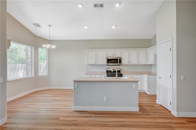 10198 Timber Willow Ave, Las Vegas, NV 89135 - kitchen with stainless steel microwave, a chandelier, white cabinetry, light countertops, and light wood-type flooring