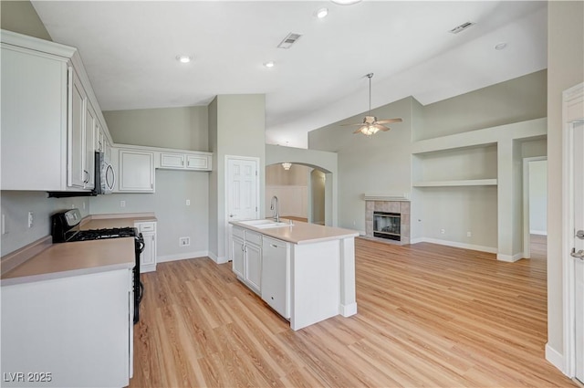 10198 Timber Willow Ave, Las Vegas, NV 89135 - kitchen with black range with gas cooktop, vaulted ceiling, a ceiling fan, stainless steel microwave, and light wood-style floors