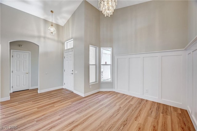 10198 Timber Willow Ave, Las Vegas, NV 89135 - foyer featuring a chandelier, light wood-type flooring, a decorative wall, a high ceiling, and arched walkways