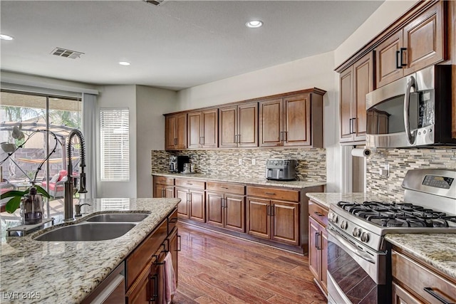 1717 Jake Andrew Ave, North Las Vegas, NV 89086 - kitchen featuring appliances with stainless steel finishes, wood finished floors, light stone counters, tasteful backsplash, and recessed lighting