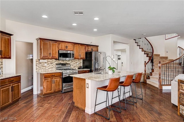1717 Jake Andrew Ave, North Las Vegas, NV 89086 - kitchen featuring appliances with stainless steel finishes, an island with sink, backsplash, dark wood-style floors, and recessed lighting
